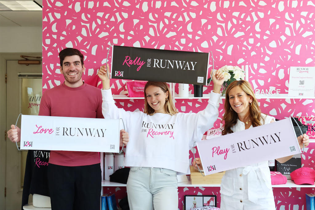 Three members of the Runway for Recovery team holding Runway for Recovery banners