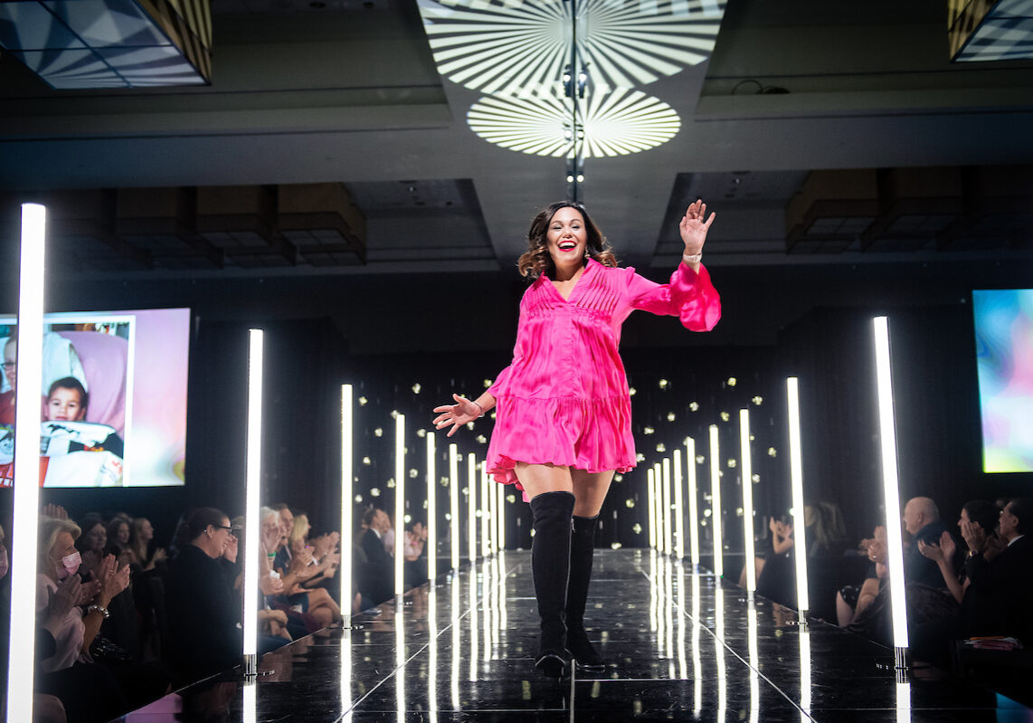 Model in pink dress walking down a runway.